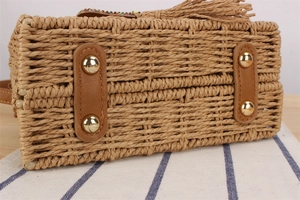 Détail du fond d'un sac en paille avec patins en cuir marron et quatre pieds dorés