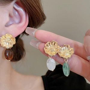 Macro shot of vintage metal flower earrings with translucent oval resin charms and gold texture