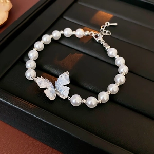 Détail d'un bracelet en perles avec pendentif papillon en cristal sur un plateau noir