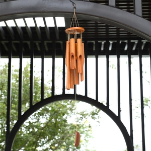 Handcrafted bamboo wind chime with wooden top and metal hook in a garden setting
