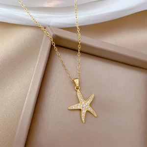 Detailed close-up of a luxury gold starfish pendant with white crystals on a beige tray