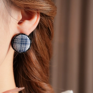 Close-up of elegant round blue plaid fabric stud earrings worn on model's ear
