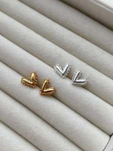 Detailed close-up of gold and silver heart-shaped 925 sterling silver stud earrings