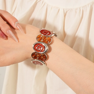 Détail macro du bracelet chaîne vintage avec motifs d'étoiles en émail rouge et orange