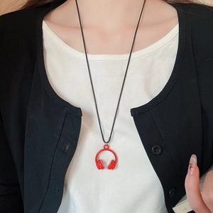 Close-up of a model wearing a red headphone-shaped pendant necklace with a black cord chain