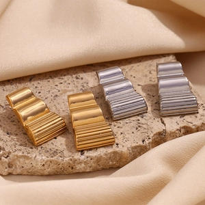 Detailed view of long trapezoid geometric earrings with wavy texture on stone