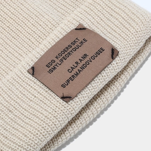 Beige knit beanie hat for winter with retro brown leather patch and thick texture