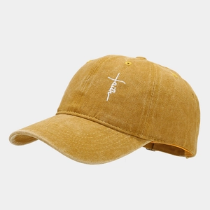 Close-up of white faith and cross embroidery on a mustard yellow washed cotton baseball cap