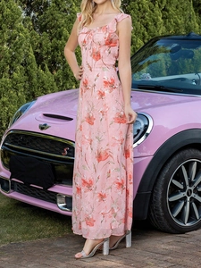 Robe longue fleurie rose avec décolleté à volants près d'une voiture rose vintage