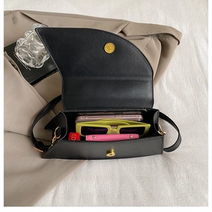Interior view of black asymmetric saddle bag showing smartphone, sunglasses, and wallet