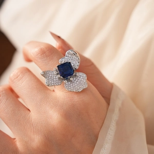 Macro detail of zircon flower ring with square blue stone and silver diamond petals