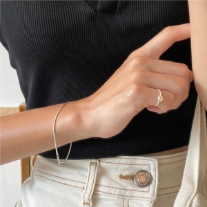 Macro shot of 925 silver ring with yellow gemstone and fine chain bracelet worn by model
