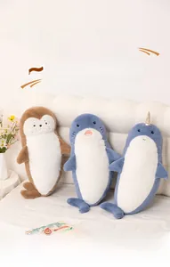 Detail of plush sea lion, shark, and narwhal pillows on bed with cozy home decor