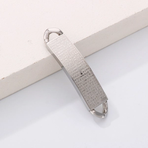 Polished stainless steel cross pendant with engraved Lord’s Prayer on textured stone background
