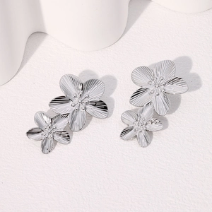 Detailed macro view of silver-toned double-layered floral earrings with brushed texture