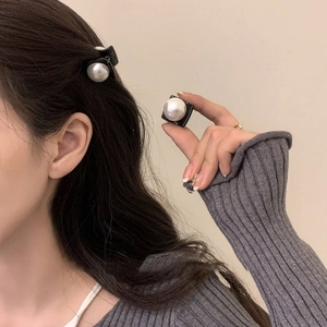 Detail of mini black pearl hair clip shown on hand for scale and on hair as side decoration