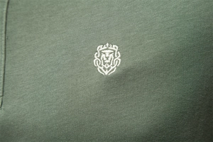 Vue macro du logo lion blanc brodé sur le tissu en coton vert armée du polo