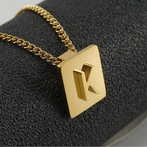 Close-up of gold square letter K pendant on a chunky Cuban chain with metallic luster