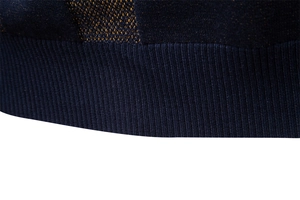 Détail de l'ourlet en tricot jacquard bleu foncé et or avec texture côtelée pour homme
