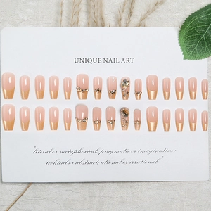 French press-on nails in nude with gold tips and rhinestones in long coffin shape