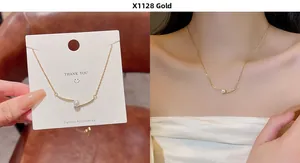 Close-up of a gold necklace featuring a minimalist curved bar with a white pearl pendant