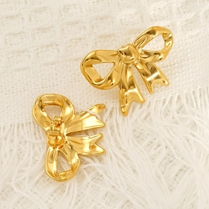 Minimalist 18k gold plated stainless steel bow earrings set on white textured fabric