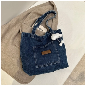 Détail du sac cabas en denim avec poche frontale et pendentif nuage en peluche