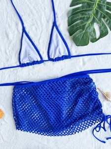 Detail of royal blue bikini top and mesh sarong set on white sand background