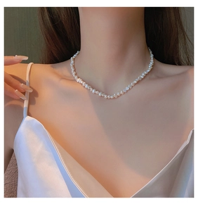 Elegant baroque pearl necklace worn by a model in warm golden lighting and satin top