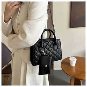 Detailed view of black quilted tote bag with detachable coin purse on tweed outfit