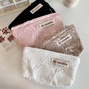 Macro shot of 3D embossed rose pattern on minimalist makeup bags in four colors