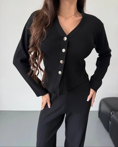 Detailed view of black knitted V-neck cardigan with four silver buttons and ribbed texture