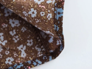 Macro shot of brown floral chiffon fabric showing blue flower pattern and fine stitching