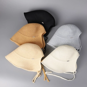 Flat lay of knit bucket hats in five colors with woven straps and metal logos