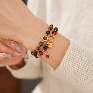 Détail de perles en oeil de tigre et pendentifs dorés sur un bracelet pour femme