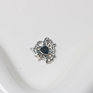 Macro detail of silver spider web heart pendant with black gemstone and tiny rhinestones