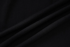 Détail rapproché du tissu en maille côtelée noire montrant la texture et l'élasticité