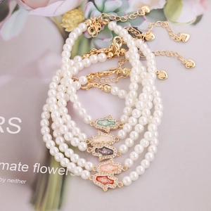 Five-piece pearl bracelets featuring colorful Hamsa Hand charms and gold-tone alloy chain
