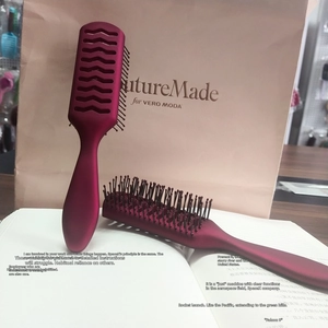 Dettaglio di spazzole bordeaux con design traforato e impugnatura ergonomica lunga