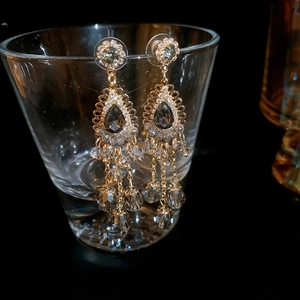 Detailed macro of vintage tassel earrings with gray teardrop stones and gold chain fringe
