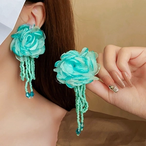 Detailed view of mint green fabric flower earrings with matching beaded tassel strands