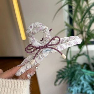 Detailaufnahme der Blumenstoff-Haarklammer mit lila Schleife und Markenetikett