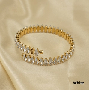 Detailed macro of 18K gold plated open bracelet with marquise-cut zircon stones on silk