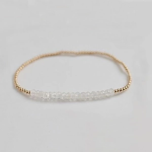 Macro detail of elastic beaded bracelet featuring natural white stones and gold accents