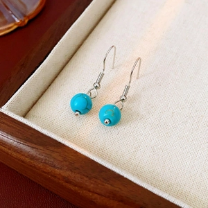Détail de boucles d'oreilles bohèmes avec perles de turquoise et crochets en argent