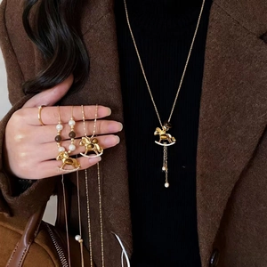 Elegant rocking horse necklace with tiger eye stone and pearls on a brown cashmere coat