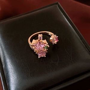 Detailed close-up of rose gold star ring with pink zircon on black leather box