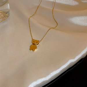 Dettaglio del ciondolo a forma di orsetto d'oro su seta con eleganti trame drappeggiate