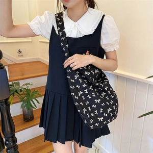 Detail of canvas crossbody bag with white bow print and wide shoulder strap design