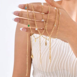 Detail of 18K gold-plated anklets with colorful rainbow gemstones on a delicate chain